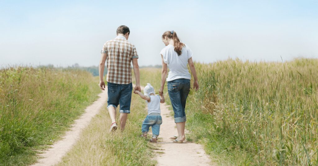 Family of three walking down road.