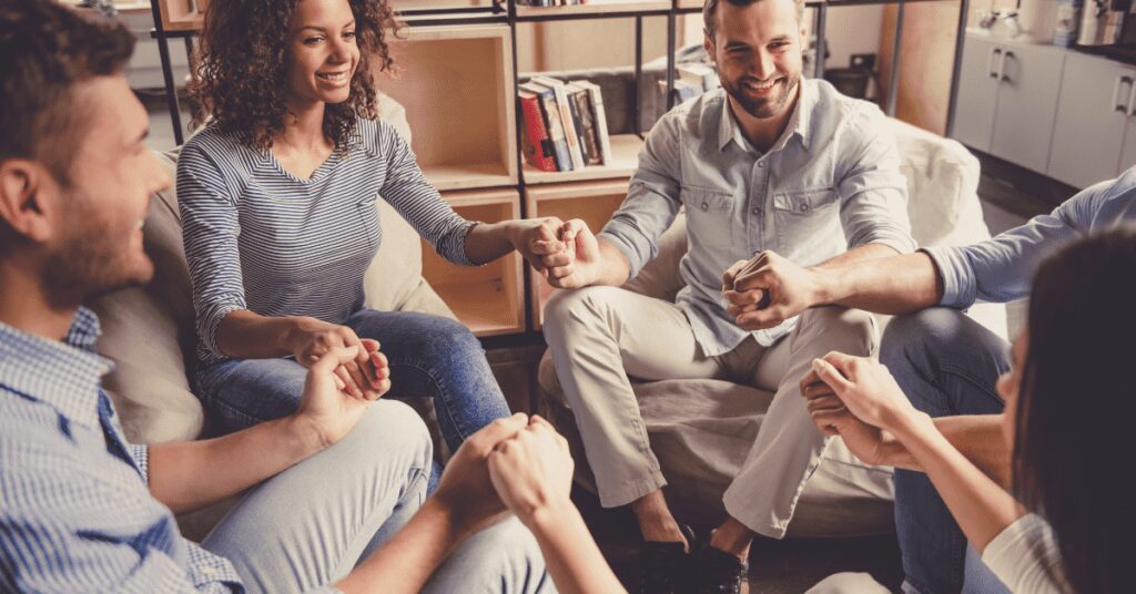 People seated holding hands.