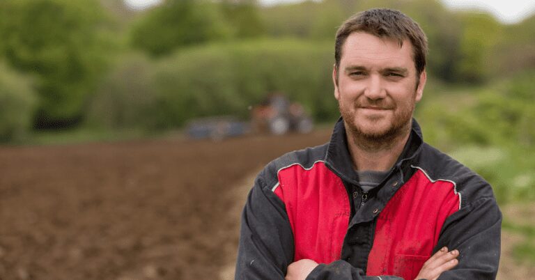 Man standing in front of tilled field.
