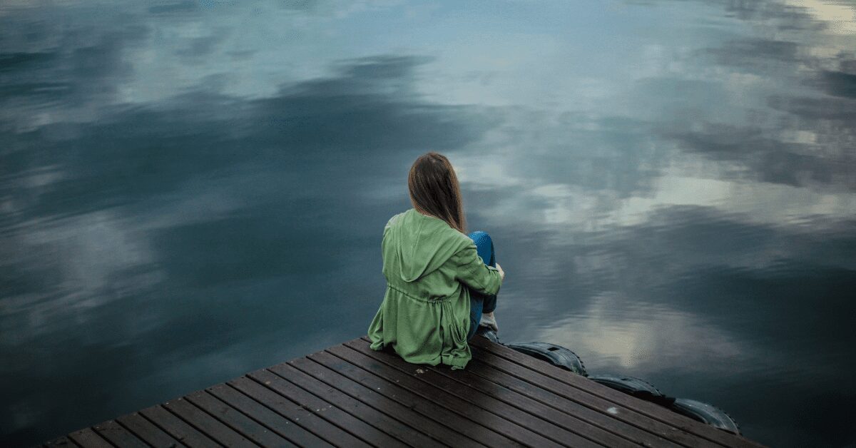 Woman seated alone on a dock.