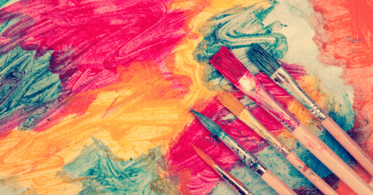 Paintbrushes sitting on abstract swirls of paint.