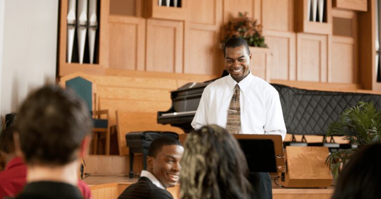 Man at music stand talking to a church.