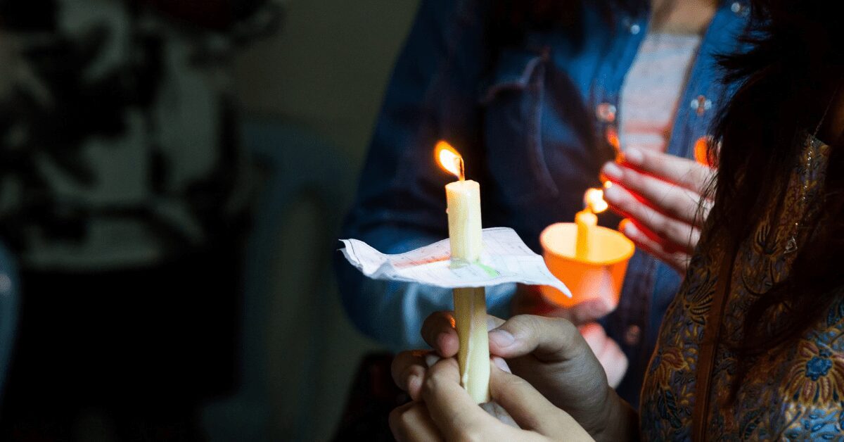 Closeup of women holding lit candles.