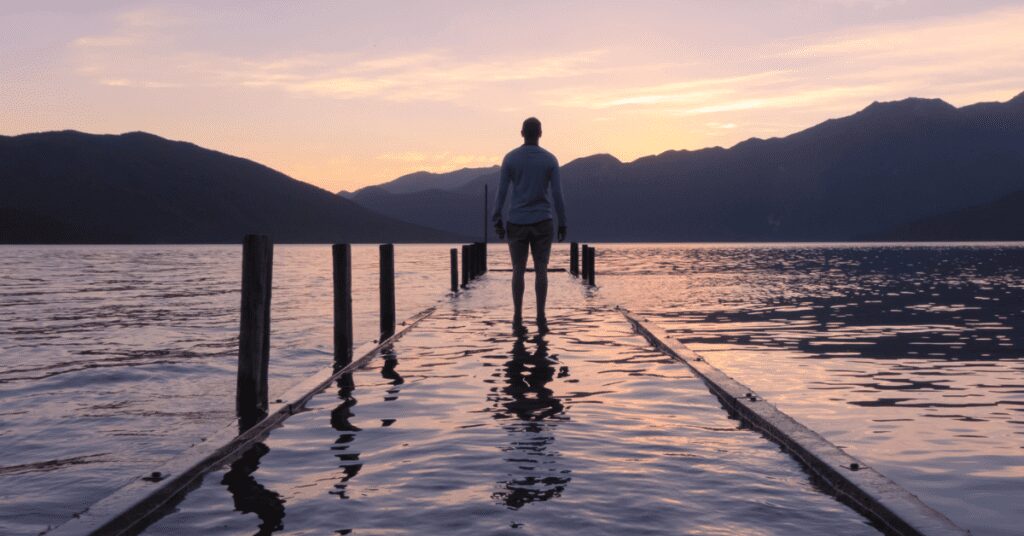 Person standing on flooded lake pier.