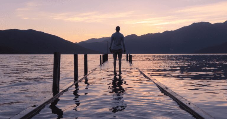 Person standing on flooded lake pier.