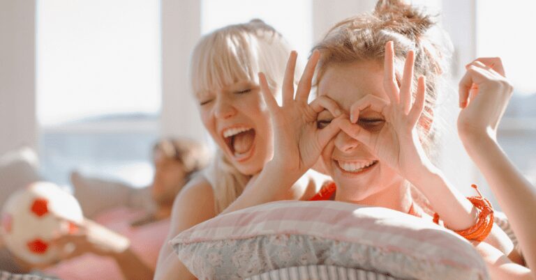 Two women laughing while one playfully covers her eyes.