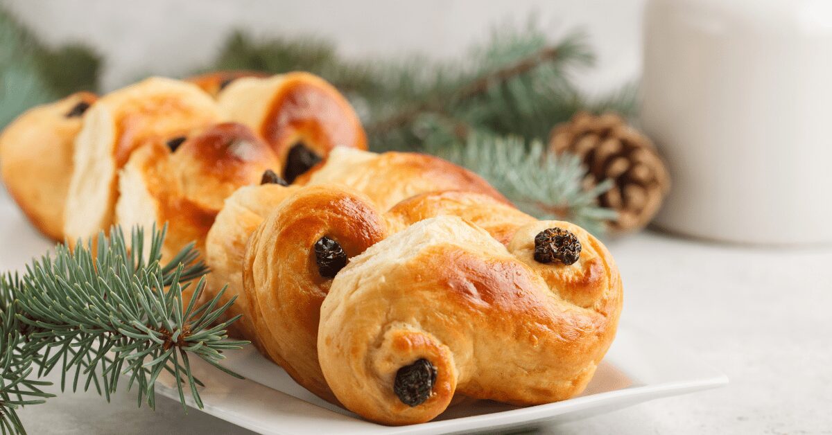 Cardamom buns on a platter with decorative fir tree branches on a table.