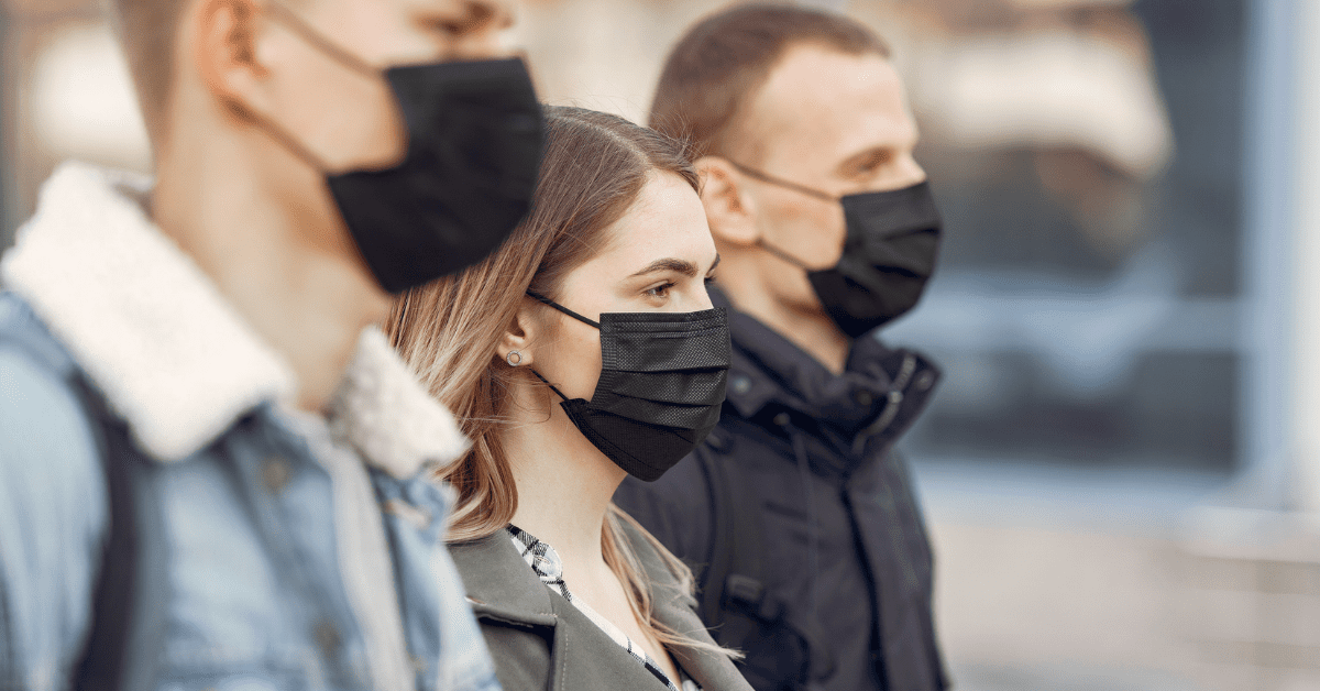 Three people in profile outside wearing masks.
