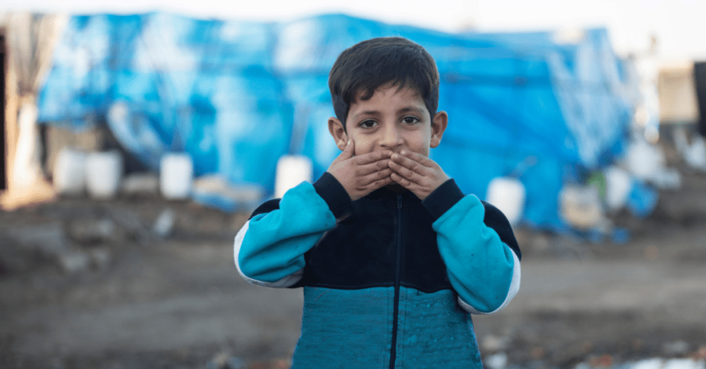 child with hands covering mouth