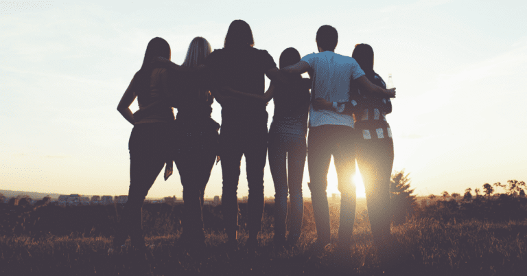 group of hugging young people watching the sunset