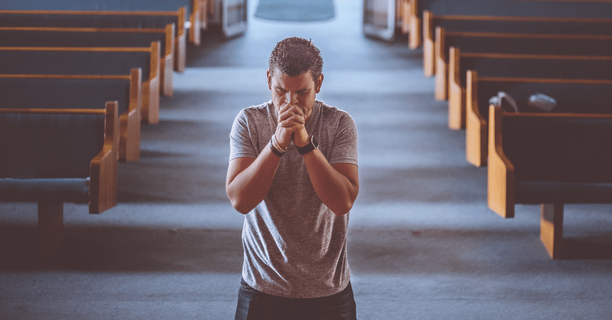 young man praying in the middle of church