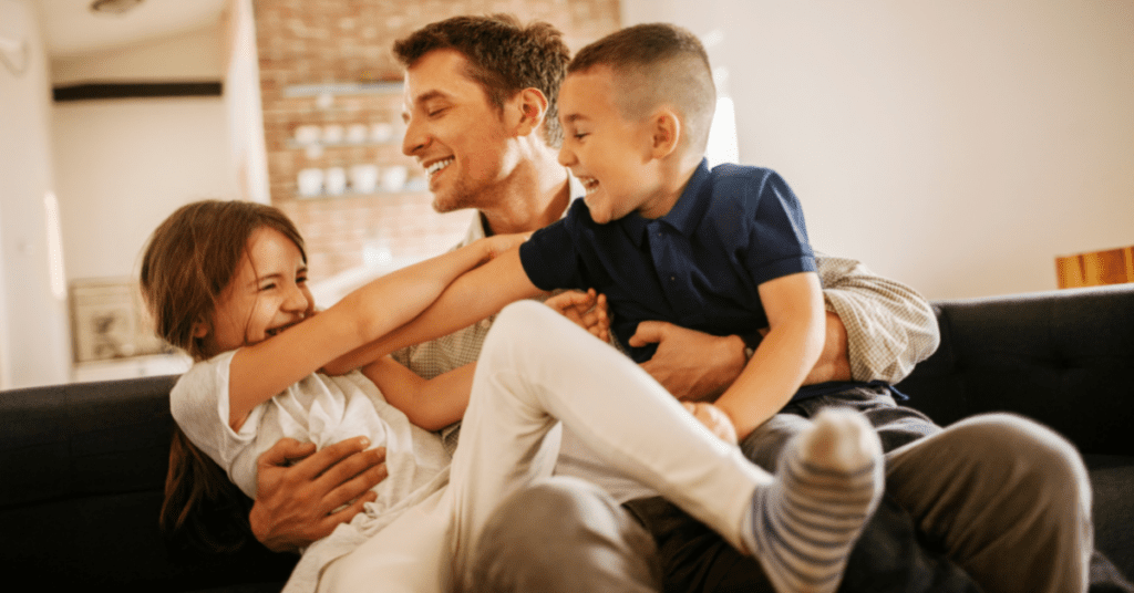 dad laughing and playing with his two small children