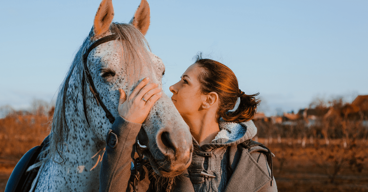 woman face to face and petting a spotted pony