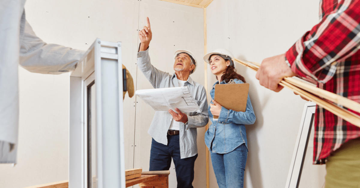 man and woman in hardhats looking at remodeling a room