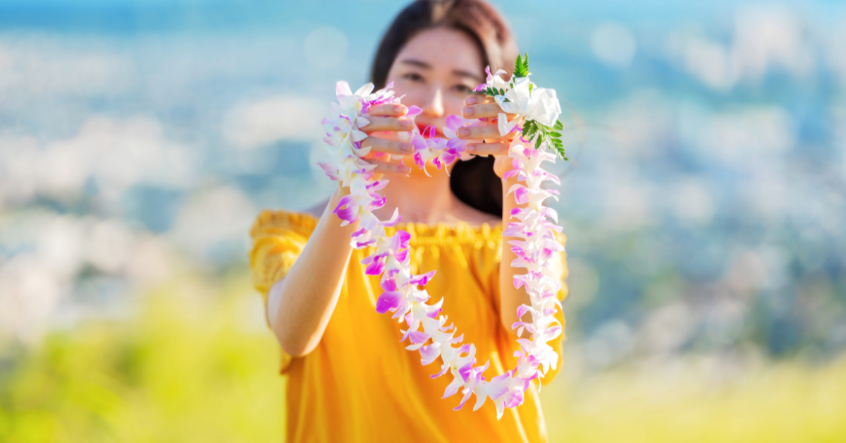 woman in a tropical setting holding up a lei