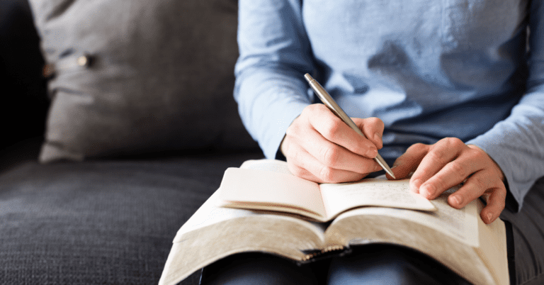 person taking notes in a Bible