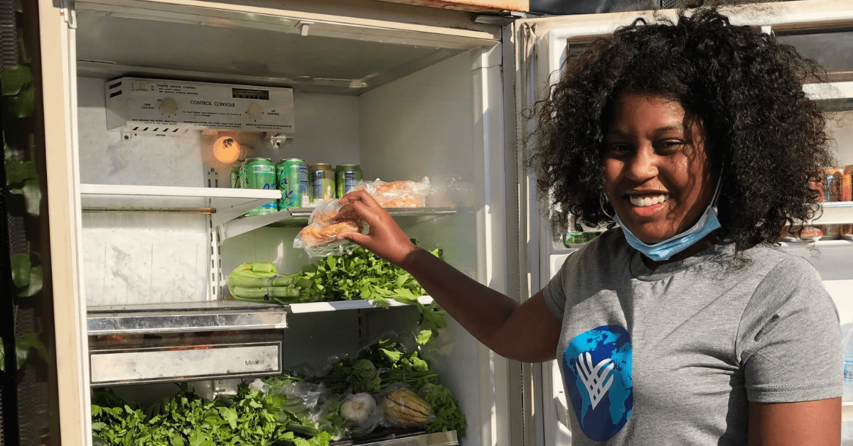 volunteer filling a community fridge with perishables