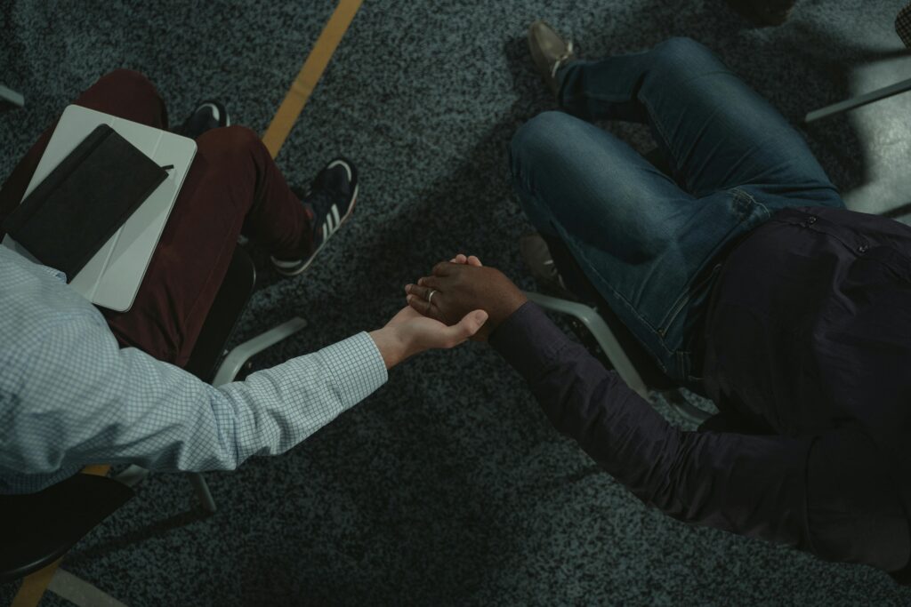 Overhead image of two people sitting in chairs holding hands in the middle of the frame.