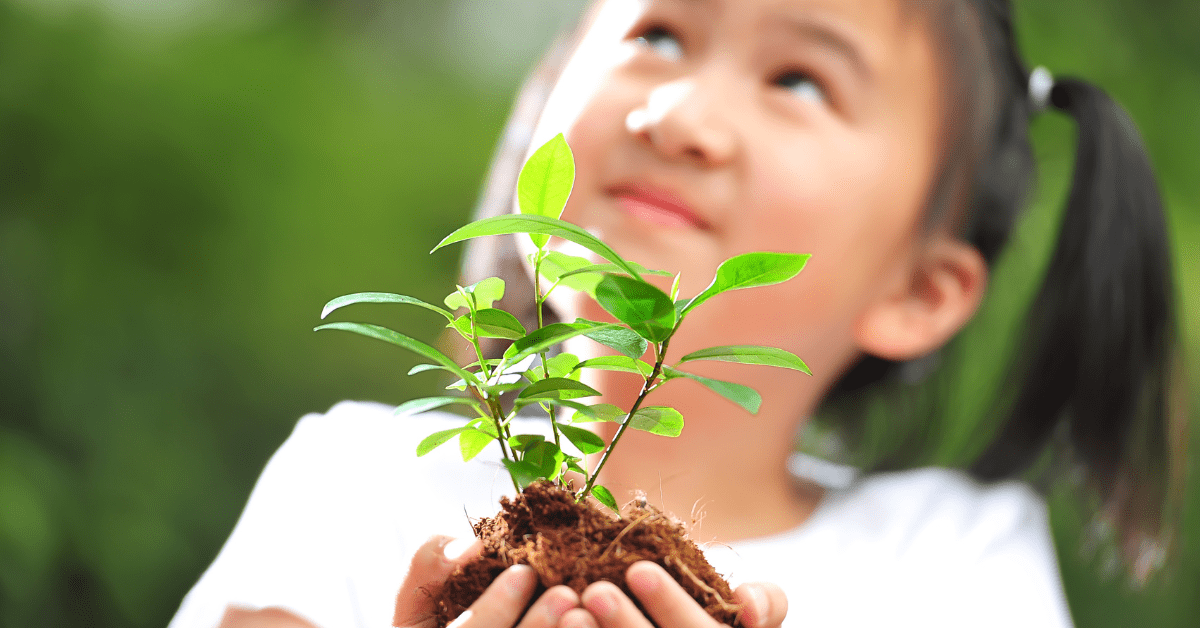 young girl holding a growing plant with soil