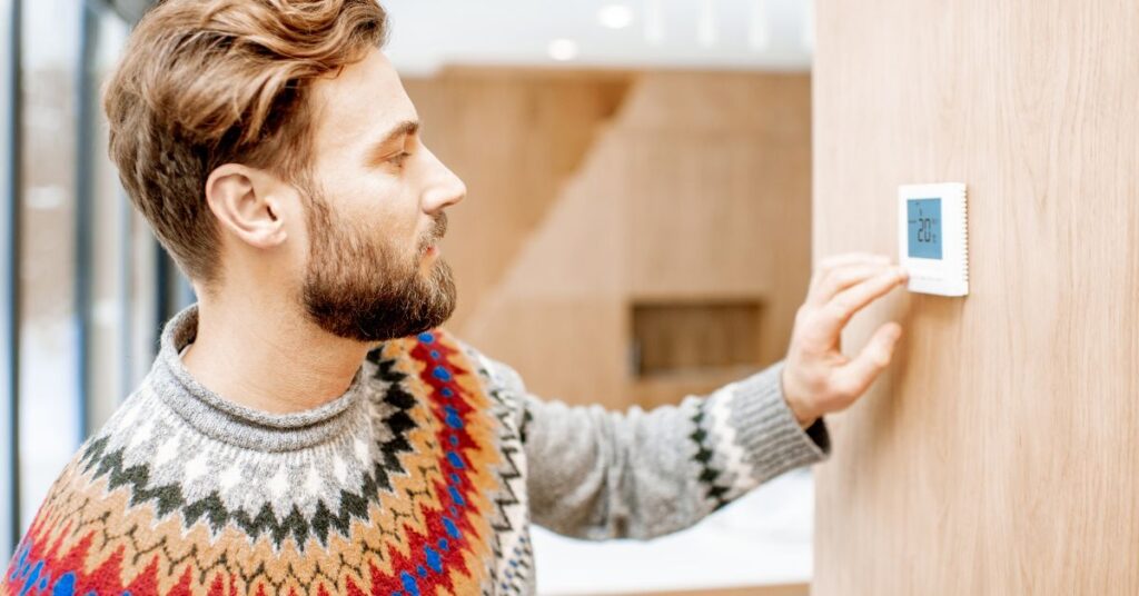 young man adjusting a thermostat