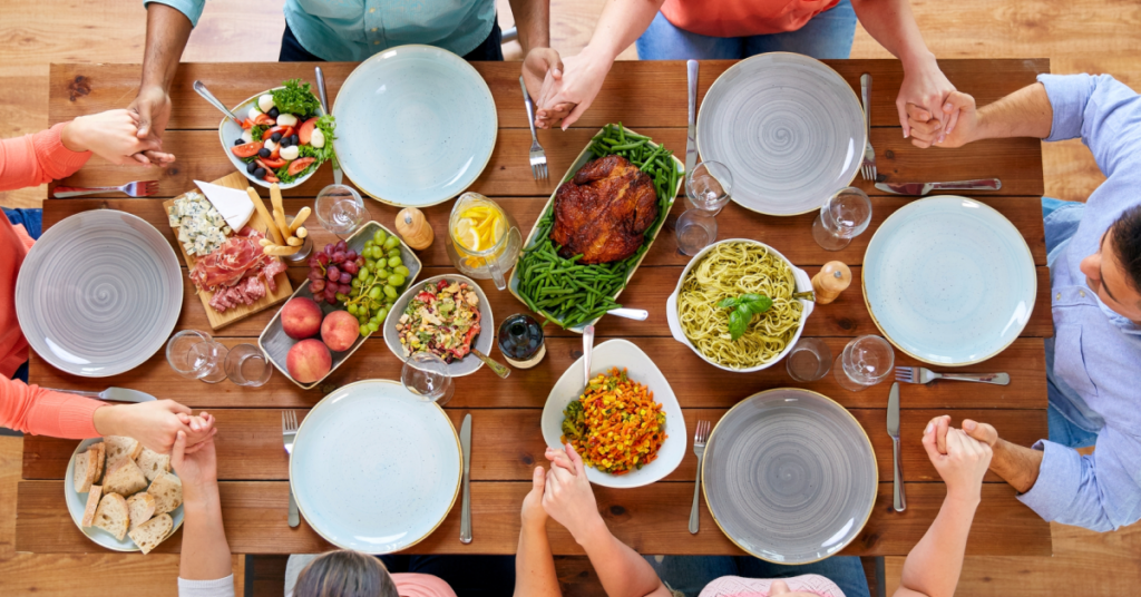 a group of people sitting down together to say grace before serving dinner