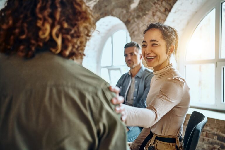 Close-up view of a back of a young man and friends supporting him during group therapy stock photo