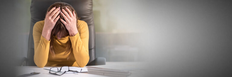 Woman with head in hands sitting at desk