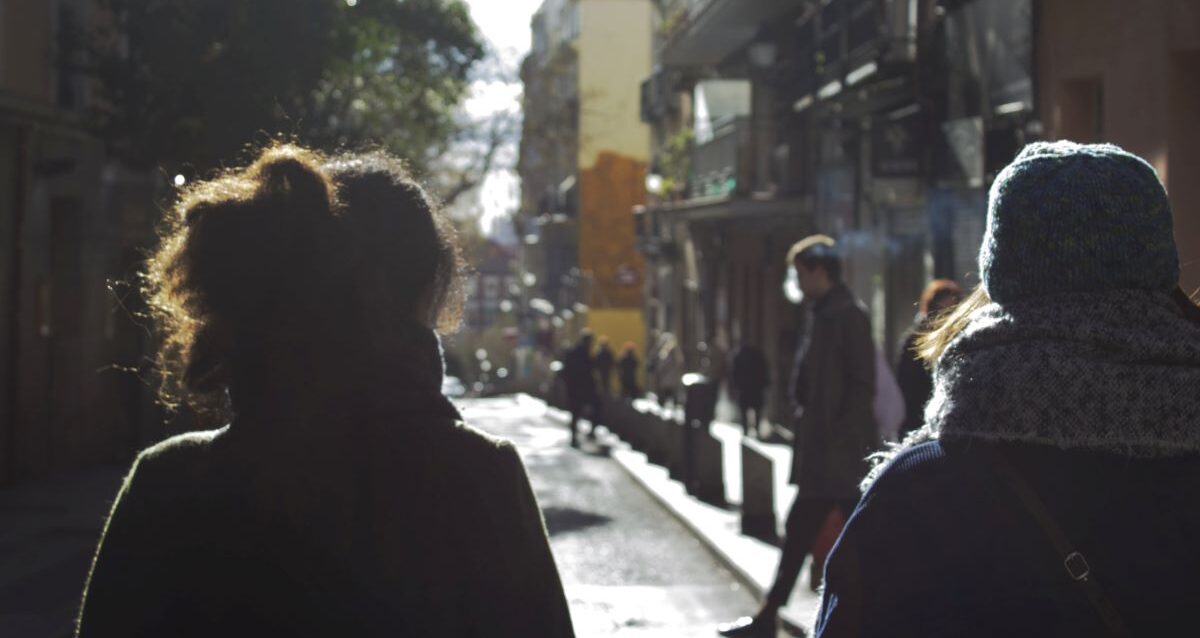 Alt: ﻿Faith+Lead | ﻿A view from behind two people bundled up in cold weather and walking down a small street in their community.