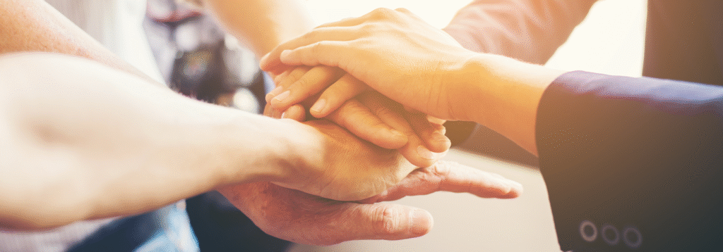 Stacked hands symbolizing teamwork in warm lighting.