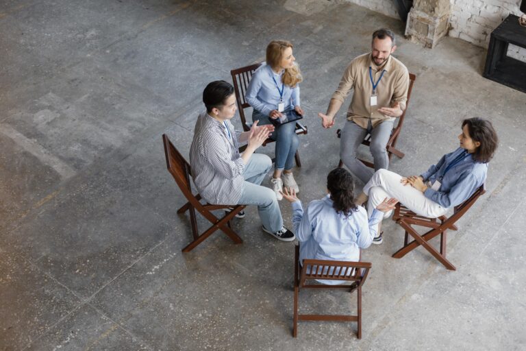 High-angle shot of a diverse group of five people sitting in a circle and engaging in a discussion.