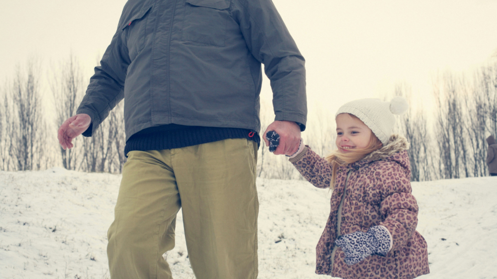 photo of an older man holding a little girl's hand in winter