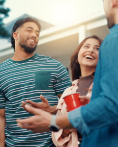 A small group of smiling friends chatting casually outdoors.