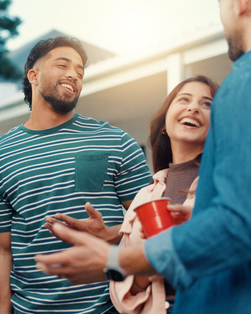 A small group of smiling friends chatting casually outdoors.