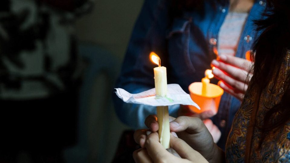 Closeup of women holding lit candles.