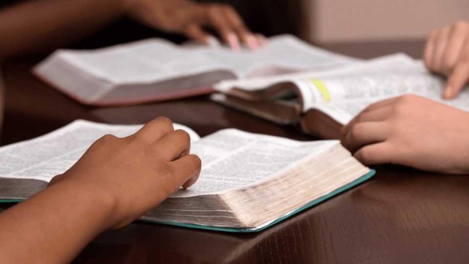 closeup of hands on top of open Bibles during a bible study