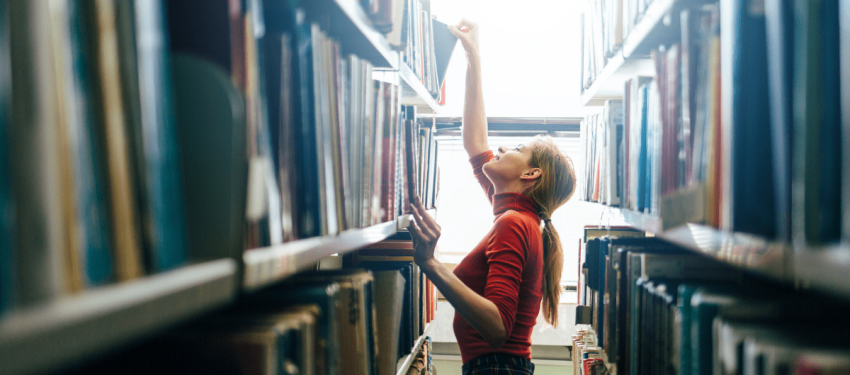 woman looking through library shelves