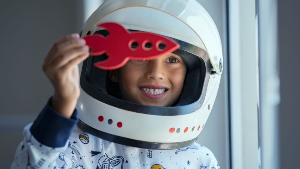 young child playing in an astronaut helmet