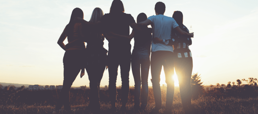 group of hugging young people watching the sunset